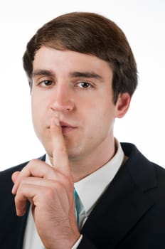Head and shoulders portrait of a young man in a black suit against white background is finger demanding to silence on the oral legend.