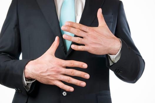 Chest-and-stomach view of a young man in a black suit with his hands held in front of him indicating the "10"" (ten fingers)"