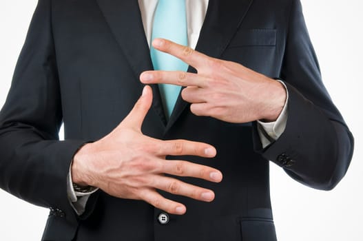 Chest-and-stomach view of a young man in a black suit with his hands held in front of him indicating the "7"" (seven fingers)"