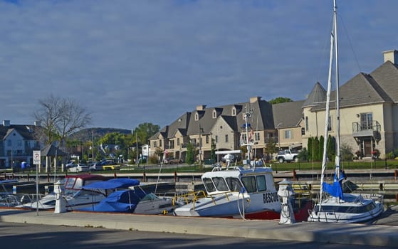 A picture of a yacht harbour in Hamilton, Ontario, Canada with a new.subdivision in the back, under sunshine in the fall..