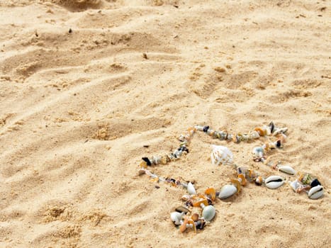 Star from cockleshells and sea pebbles laid out on sand
