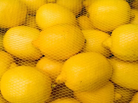 A pile of beautiful lemons in the grid on a counter