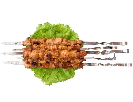 The shish kebab on skewers and greengrocery isolated on the white background