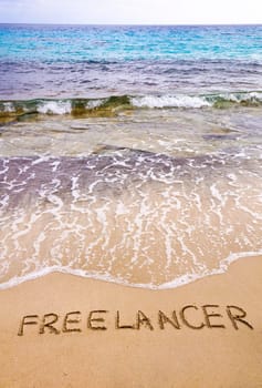 Word FREELANCER written in sand, on a beautiful beach, Freelance concept