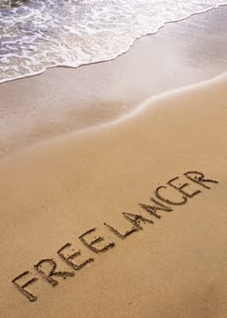 Word FREELANCER written in sand, on a beautiful beach, Freelance concept