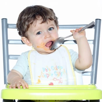 Details of a young boy sitting on a chair and playing with a spoon.