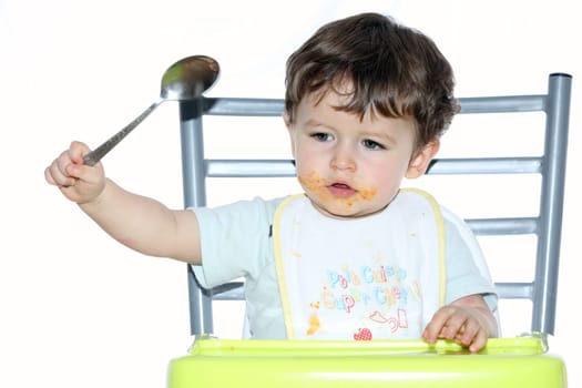 Details of a young boy sitting on a chair and playing with a spoon.