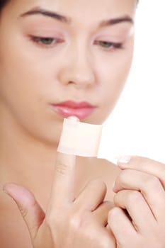 Pretty young woman using adhesive plaster on her injured finger.