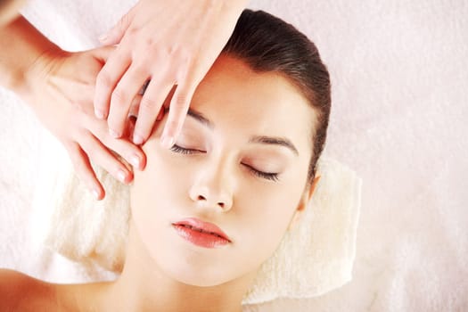 Beautiful young relaxed woman enjoy receiving face massage at spa