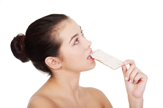 Young pretty woman eating healthy rye cracker bread and looking up on copy space