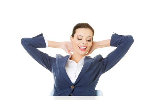 attractive woman sitting with her hands behind her neck. isolated onw hite.