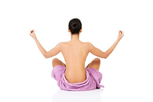 Attractive naked woman sitting in towel.Back view.  Isolated on white.