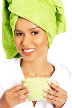 attractive woman wrapped in towel on head with a turban,holding a cup. isolated on white.