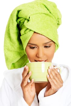 attractive woman wrapped in towel on head with a turban,holding a cup. isolated on white.