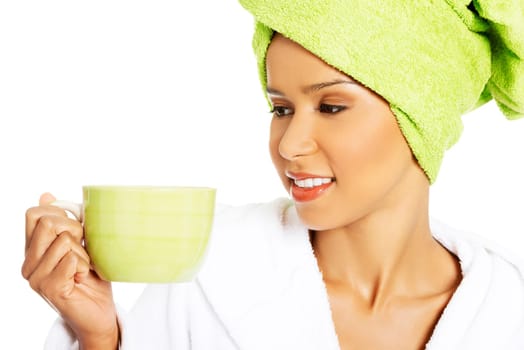 attractive woman wrapped in towel on head with a turban,holding a cup. isolated on white.