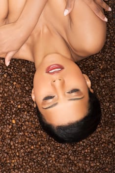 attractive woman lying upside down on coffee seeds.