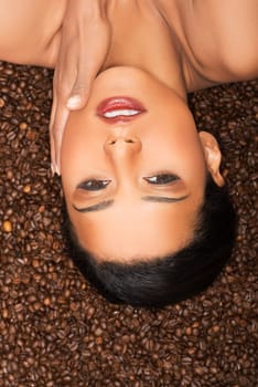 attractive woman lying upside down on coffee seeds. closeup.