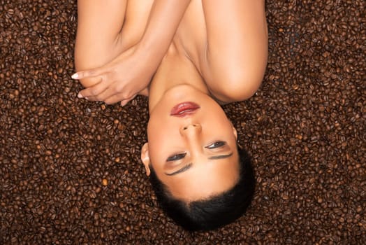 attractive woman lying upside down on coffee seeds. closeup.