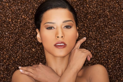 attractive woman lying in coffee grains. fron view. closeup.