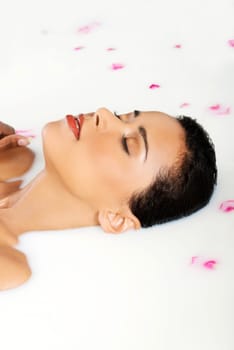 attractive naked woman lying in a bath. with rose petal. up front view.
