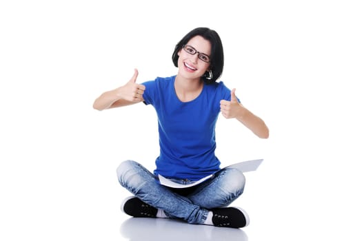 female student with workbook on knees showing ok. isolated on white.