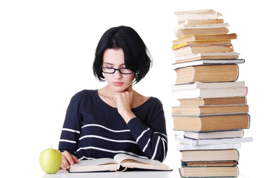arrtactive young woman sitting next to stack of book with an apple. isolated on white.