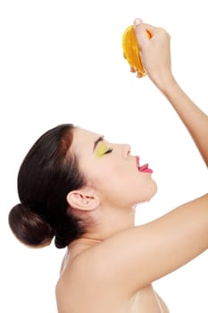 attractive woman squeezing orange juice straight to mouth. isolated on white.
