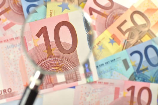 euro banknotes under magnifying glass