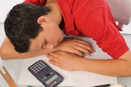 Boy sits exhausted and frustrated about homework at desk in front of a white background