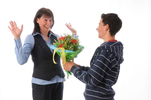 Mother and her teenage son,he presents her with a bouquet of flowers against a white background