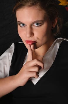 A young girl with a blouse and boots sits teasingly on a black leather armchair against a dark background