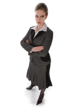 Young woman in grey business suit and high heels poses with folded arms against a white background