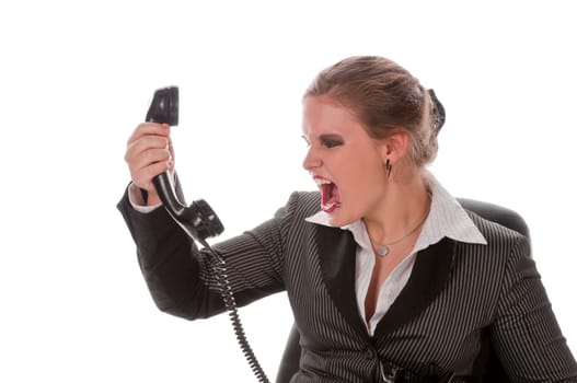 Young woman in grey business suit and high heels makes calls with landline telephone and yells angrily into the receiver against a white background