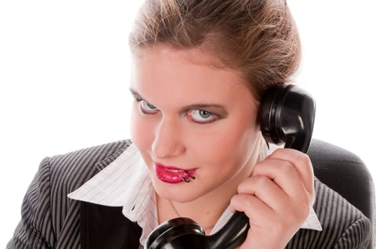 Young woman in grey business suit and high heels making calls with landline telephone against a white background