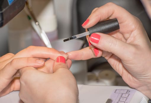 Manicure treatment and red color drawing in cosmetic saloon