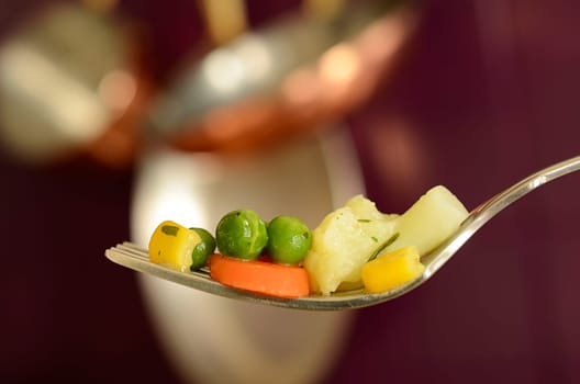 Cooked vegetables on a fork in a kitchen