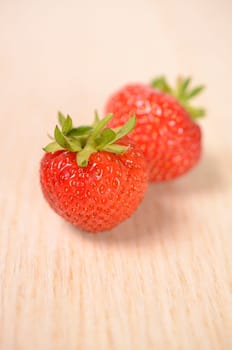 Two fresh strawberries on a wooden background