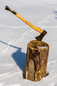 Ax stuck in wood log snow winter