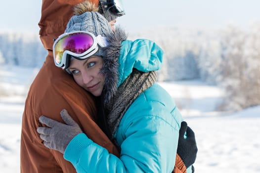 Young couple ski goggles embracing in winter snow countryside