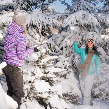 Two girlfriends throw snow balls winter forest enjoy holiday break