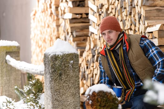 Young handsome man posing winter fashion wooden logs country