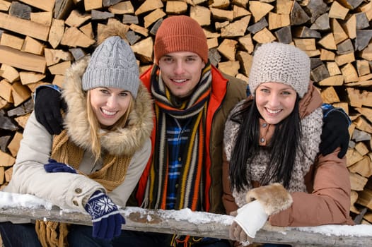 Young people in winter clothes posing outside wooden logs countryside