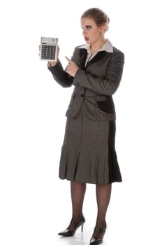 Young woman in a grey business suit and high heels looks horrified at her large calculator against a white background