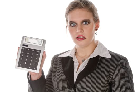 Young woman in a grey business suit and high heels looks horrified at her large calculator against a white background