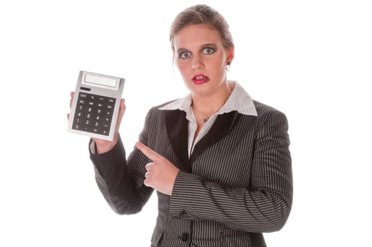 Young woman in a grey business suit and high heels looks horrified at her large calculator against a white background