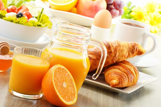 Breakfast with coffee, orange juice, croissant, egg, vegetables and fruits