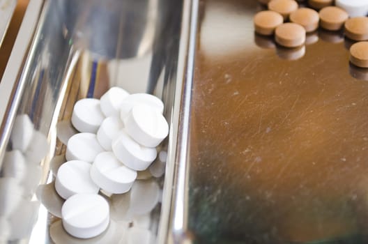 Close up of Counting tablets medical pills on stainless steel tray.(Health care and medical concept)