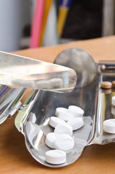 Close up of Counting tablets medical pills on stainless steel tray.(Health care and medical concept)