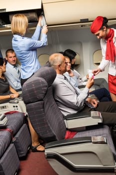 Flight attendant check passenger tickets in plane cabin