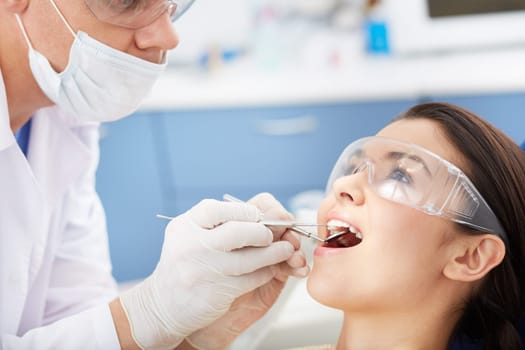 Young girl with open mouth during oral checkup at the dentist’s